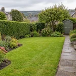 A maintained Shipley garden with a lawn, planted borders, trimmed hedge and stone path.