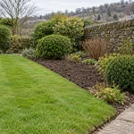 A Thackley garden with a maintained lawn, cleared planting bed and established shrubs.